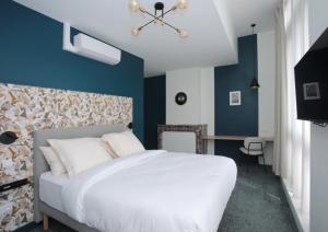 a bedroom with a white bed and blue walls at Motte Fénelon Appart in Cambrai