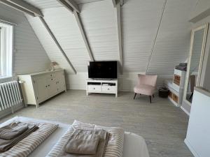 ein Schlafzimmer mit einem Bett, einem Fernseher und einem Stuhl in der Unterkunft Ferienhaus Berg in Sylt