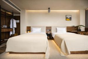 two beds in a hotel room with white sheets at 大有观于All about Yu Hotel in Chongqing