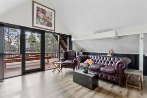 Una sala de estar con dos sofás de cuero y un balcón. en Spacious Barossa Retreat with Balcony Views, en Tanunda