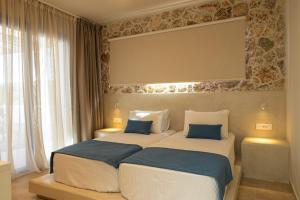 two beds in a hotel room with a large window at Villa Pollux in Gennadi +8 photos
