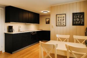 a kitchen with black cabinets and a table and chairs at Leilighet sentralt i Bud in Bud