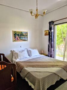 a bedroom with a bed with a chandelier and a window at Sofia's Home 9min. Athens Airport in Artemida