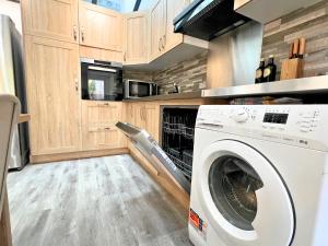 eine Waschmaschine in einer Küche mit Holzschränken in der Unterkunft Le Repaire des 12- Hypercentre, jardin, idéale groupes, 5 chambres 5 salles de bain in Saint-Omer