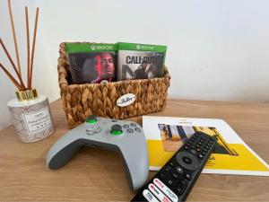 ein Videospiel-Controller neben einer Fernbedienung in der Unterkunft Le Repaire des 12- Hypercentre, jardin, idéale groupes, 5 chambres 5 salles de bain in Saint-Omer + 21 Fotos