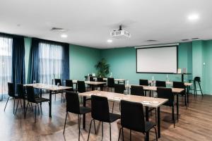 a conference room with tables and chairs and a screen at Naumi Auckland Airport Hotel in Auckland