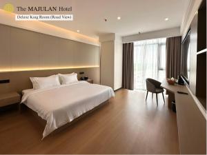 a bedroom with a large white bed and a desk at The MAJULAN Hotel in Kota Kinabalu