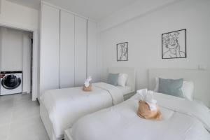 two beds in a room with white walls at Carisa Elysium Larnaca in Larnaka