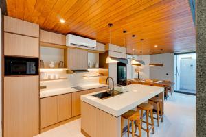 a kitchen with wooden ceilings and a kitchen island with bar stools at NEW! Luxury Modern 3BR Villa Kesatu in Canggu in Canggu