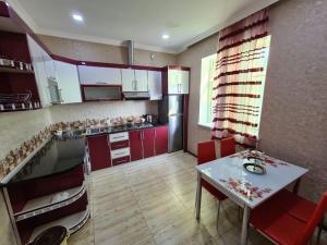 a kitchen with red cabinets and a white table with chairs at QQS villa with swimming pool in Gabala