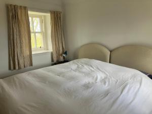 a white bed in a bedroom with a window at Berryhill West Wing- 3 bedroom - 2 bathroom - Self Catering - Sleeps 4 - Dogs Welcome - Off-road Parking - Suit Contractors - Shooting Parties - Peterhead 1 mile - Newly Refurbished - Shed - Yard -Drying Room available in Peterhead