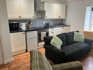 ein Wohnzimmer mit Couch und Küche in der Unterkunft Berryhill Maids Quarters - 3 bedroom - Self Catering - Sleeps 3 - Dogs Welcome - Off-road Parking - Suit Contractors - Peterhead 1 mile - Newly Refurbished - Open plan kitchen -living - dining - 2 bathroom - Shed - Yard -Drying Room available in Peterhead