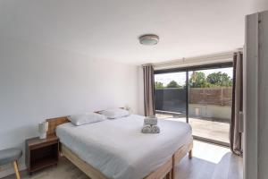 a bedroom with a bed and a large window at La Si Lancieuse - Maison spacieuse in Lancieux