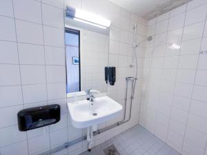 a white tiled bathroom with a sink and a phone at Lia Fjellhotell in Geilo +27 photos