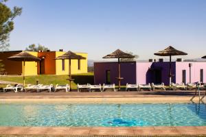 a pool with chairs and umbrellas in front of buildings at Mobility Friends Hostel in Barcelos