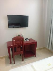 a red desk with a chair and a tv on a wall at Rising Sun Hotel in Mwanza