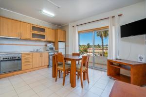 una cucina con tavolo, sedie e televisione di Apartamentos Santa Teresinha ad Alvor