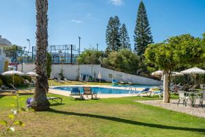 una piscina con sedie e ombrelloni in un parco di Apartamentos Santa Teresinha ad Alvor