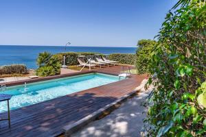 a swimming pool with a wooden deck and the ocean at Vero Sicily - Villa Acqua Chiara in Bagheria