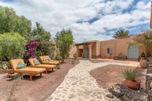 Un patio con bancos y flores frente a una casa. en Oasis San Martin El Cotillo, en Playa del Águila