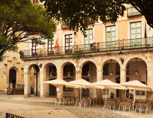 a group of tables with umbrellas in front of a building at Hotel Infanta Isabel by Recordis Hotels in Segovia