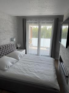 a bedroom with a large bed and a window at AKOYA APARTMENT Cristal Bianco in Koszalin