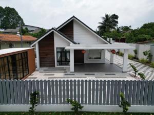 ein Haus mit einem weißen Zaun davor in der Unterkunft 189 Landed HomeStay Johor Bahru in Kampong Saleng