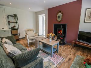 een woonkamer met een bank en een open haard bij Nithbank Cottage in Thornhill