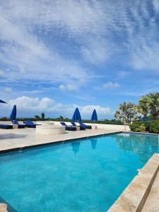 a swimming pool with blue chairs and umbrellas at Cozy Studio in TCI in Providenciales