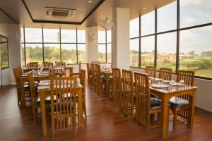 un ristorante con tavoli e sedie in legno e grandi finestre di Three Heavens Corbett a Ramnagar