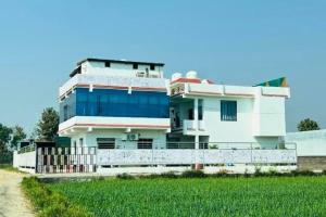 una grande casa bianca con una recinzione di fronte di Three Heavens Corbett a Ramnagar