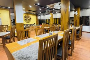 una sala da pranzo con tavoli e sedie in legno di Three Heavens Corbett a Ramnagar Altre 6 foto