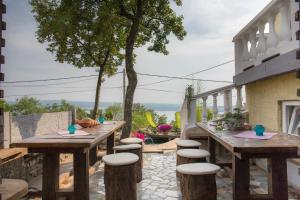a patio with wooden tables and stools at Apartman Katarina in Dramalj