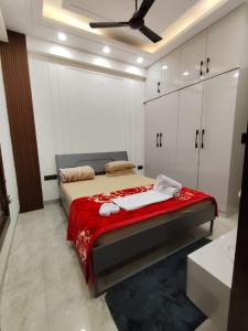 una camera da letto con un letto con una coperta rossa e armadietti bianchi di Homlee-Diamond 2BHK Lift-Parking-Max Vaishali a Ghaziabad