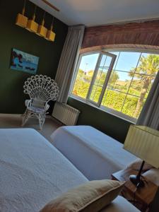 a bedroom with two beds and a chair and two windows at Apartamentos Hacienda de Arna in Somo +61 photos