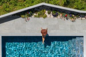 eine Person mit Hut in einem Schwimmbad in der Unterkunft Vila da Ponta do Pargo by An Island Apart in Ponta do Pargo