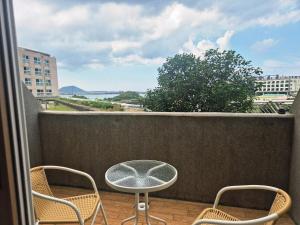 Un patio con una mesa y sillas en un balcón. en Relaxing Sunset Healing Ocean TerraceView, en Seogwipo