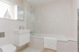 a white bathroom with a tub and a sink at St Marks Cottage in Swanage +21 photos