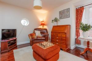 a living room with a chair a dresser and a tv at St Marks Cottage in Swanage