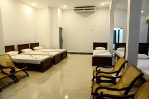 a room with three beds and chairs in it at Crocodile park Bungalow in Kataragama