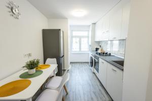 a kitchen with white cabinets and a table and chairs at Apartament Lucas Sighișoara in Sighişoara