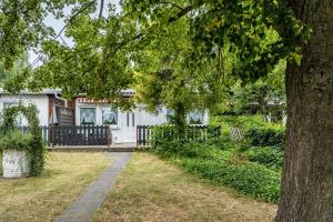 a white house with a tree and a sidewalk at Bungalow 91 in Stelzendorf