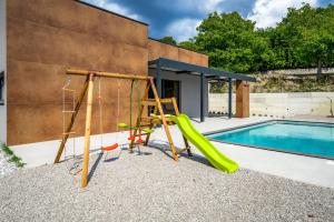 a playground with a slide and a swing set next to a swimming pool at Casa Pianta in Buzet - Haus für 6 Personen in Buzet