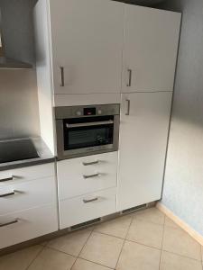 a kitchen with white cabinets and a microwave at maison en campagne in Vernois-lès-Belvoir
