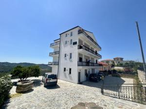 a white building with a car parked in front of it at Ishëm Greenview Apartments in Draçi