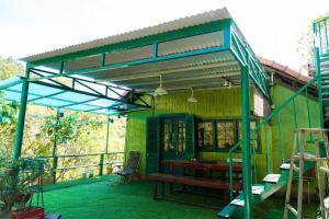 a green building with a bench and a table at Ở Đây Thôi - Homestay Đà Lạt in Manline +10 photos