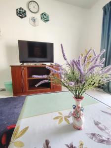 a vase with purple flowers sitting on a table at Bayu Biru 2 Bedroom Unit Pool View Balcony in Kampong Tanah Merah