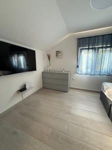 a large white room with a bed and a television at Golden Wave Apartment in Vir