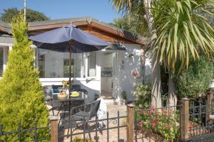 a patio with a table and an umbrella at Lucy Lou, charming holiday bungalow in Devon in Galmpton-on-the-Dart