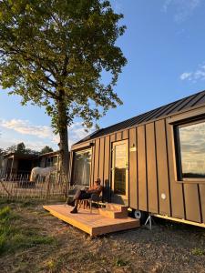 a man sitting in a chair in front of a trailer at Tinyhouse in der Natur in Hahn bei Marienberg